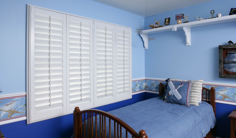Large plantation shutters covering window in blue kids bedroom in Fort Lauderdale 